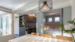 Un espacio habitable compacto con comedor, kitchenette y habitación.