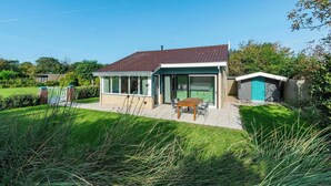 A modern house with a patio, a dining area, and a small shed.