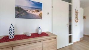 Ein Zimmer mit einem Holzkasten, einem Bild im Strandhaus-Stil und einer Wanddekoration.