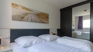 Ein Hotelzimmer mit Bett, Nachttisch, Wandgemälde und einem großen Spiegel.