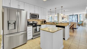 A modern kitchen with white cabinetry, stainless steel appliances, and a central island. - 123D Shipwatch by AvantStay | Beach Access + Pool (Isle Of Palms)