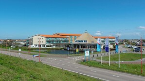 A modern hotel with a central atrium, multiple floors, and a prominent dome structure. - Cozy Stay Near Dunes (Julianadorp aan Zee)