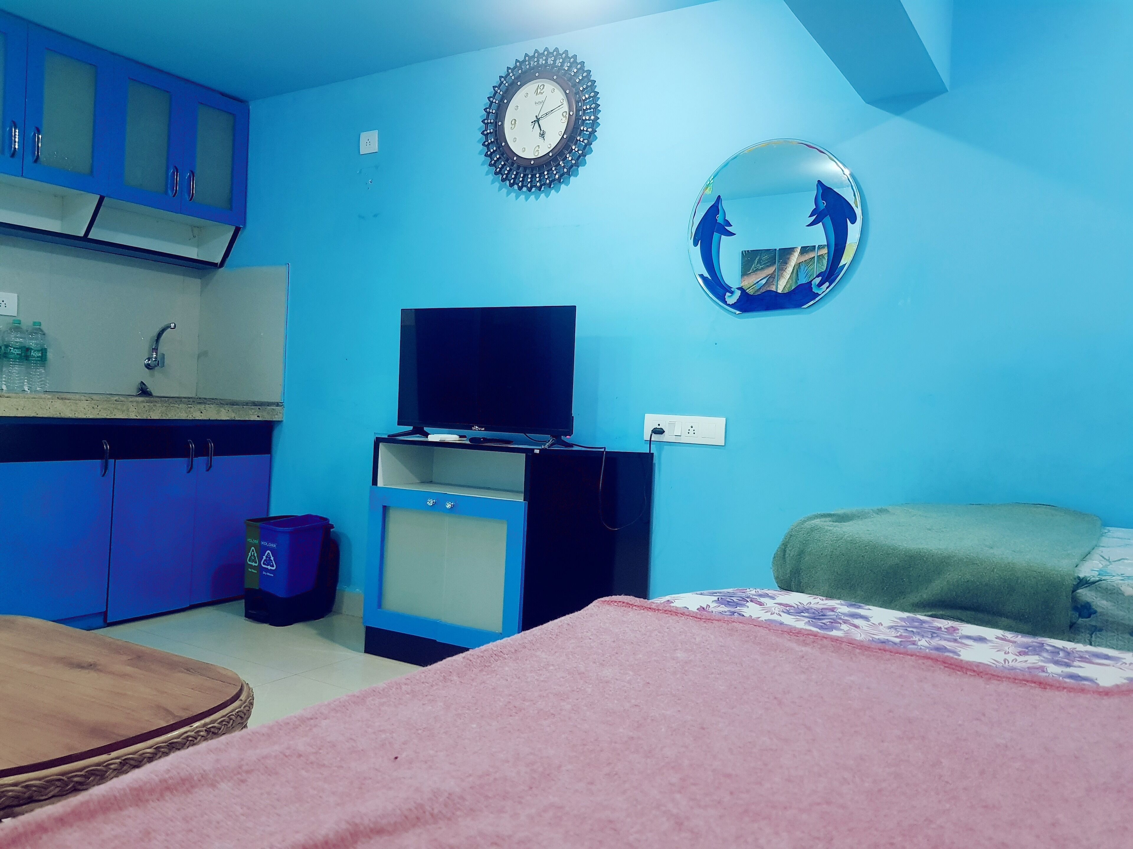 Una habitación con cama, televisión, lavamanos y armarios.
