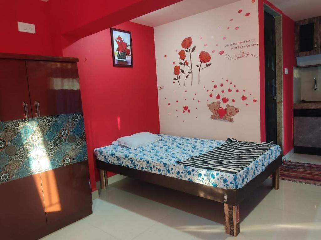 Un dormitorio con cama, armario y una pared decorada con motivos florales y de corazón.