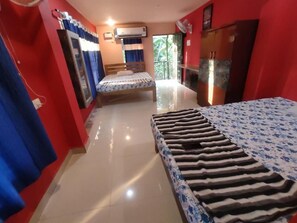 A hotel room with a bed, a wardrobe, a mirror, and a window with curtains. - Godwill Kimo Guest House (Majorda)