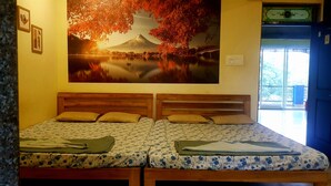A double bed with a wooden headboard, two pillows, and a floral-patterned bedspread. - Godwill Kimo Guest House (Majorda)