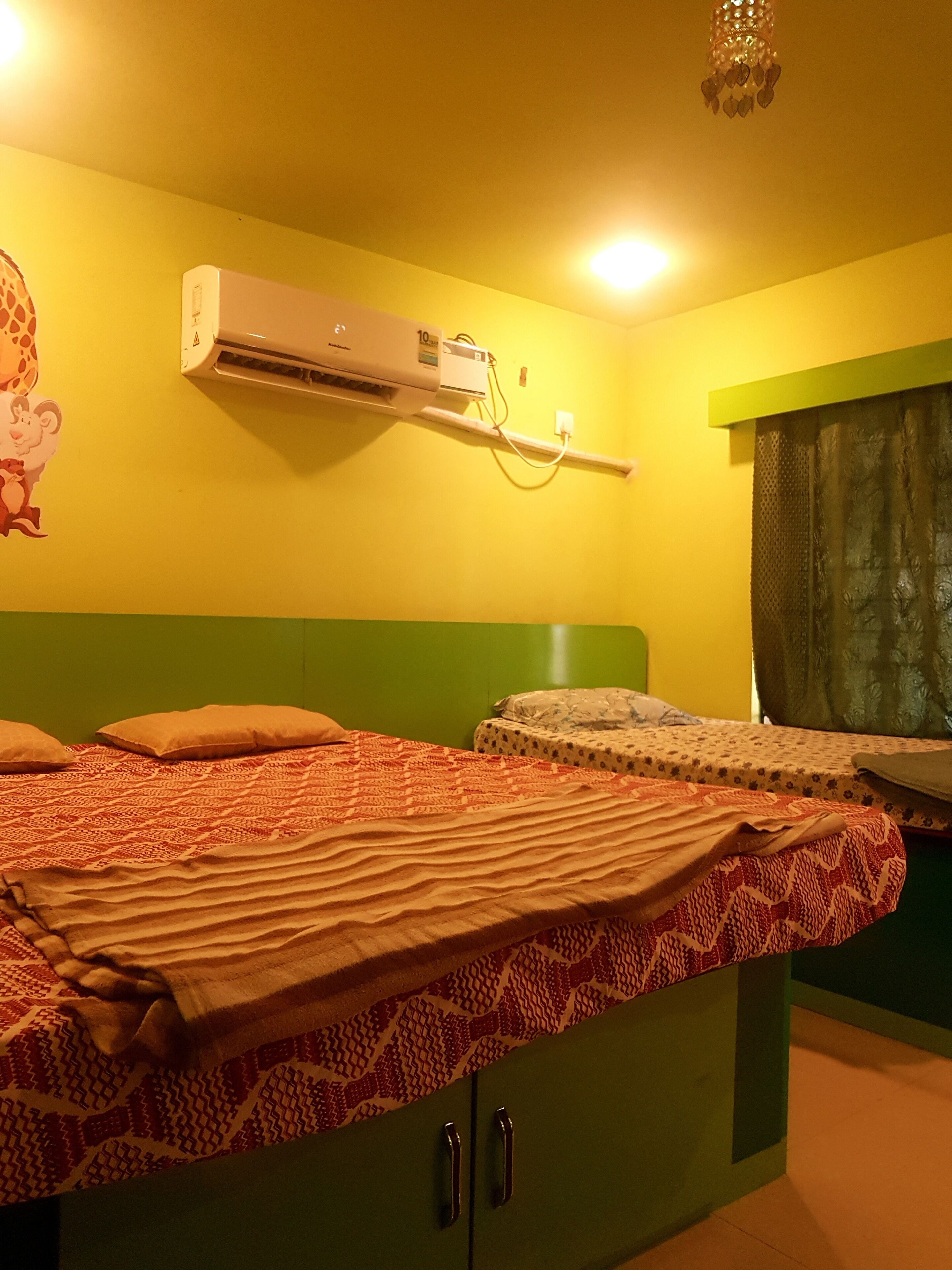 Una habitación con una cama, aire acondicionado de pared y un armario verde.