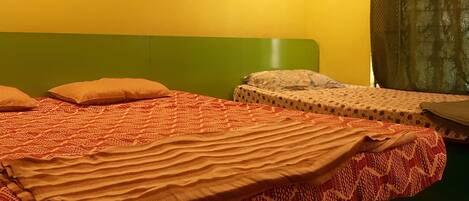 A room with a bed, a wall-mounted air conditioner, and a green cabinet.