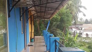 A covered corridor with blue walls and metal railings, leading to a building entrance. - Godwill Kimo Guest House (Majorda)