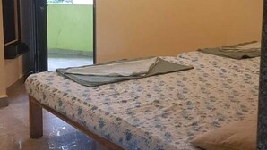 A bedroom with a bed, an air conditioner, a ceiling fan, a door, and a window. - Godwill Kimo Guest House (Majorda)