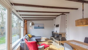 Una sala de estar acogedora con un sofá, sillas rojas, una mesa de comedor y una chimenea.