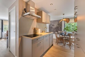 A modern kitchen with a central island, built-in cabinets, and a dining area with a view of greenery.