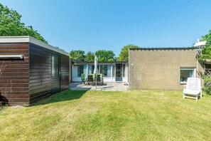 Una casa moderna con un patio, una piscina pequeña y un jardín.