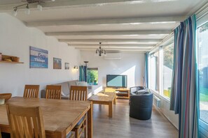 Un amplio espacio de sala con una mesa de comedor de madera, sofás y un televisor.
