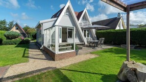 Et moderne hus med saddeltag, en overdækket terrasse og en velplejet græsplæne.