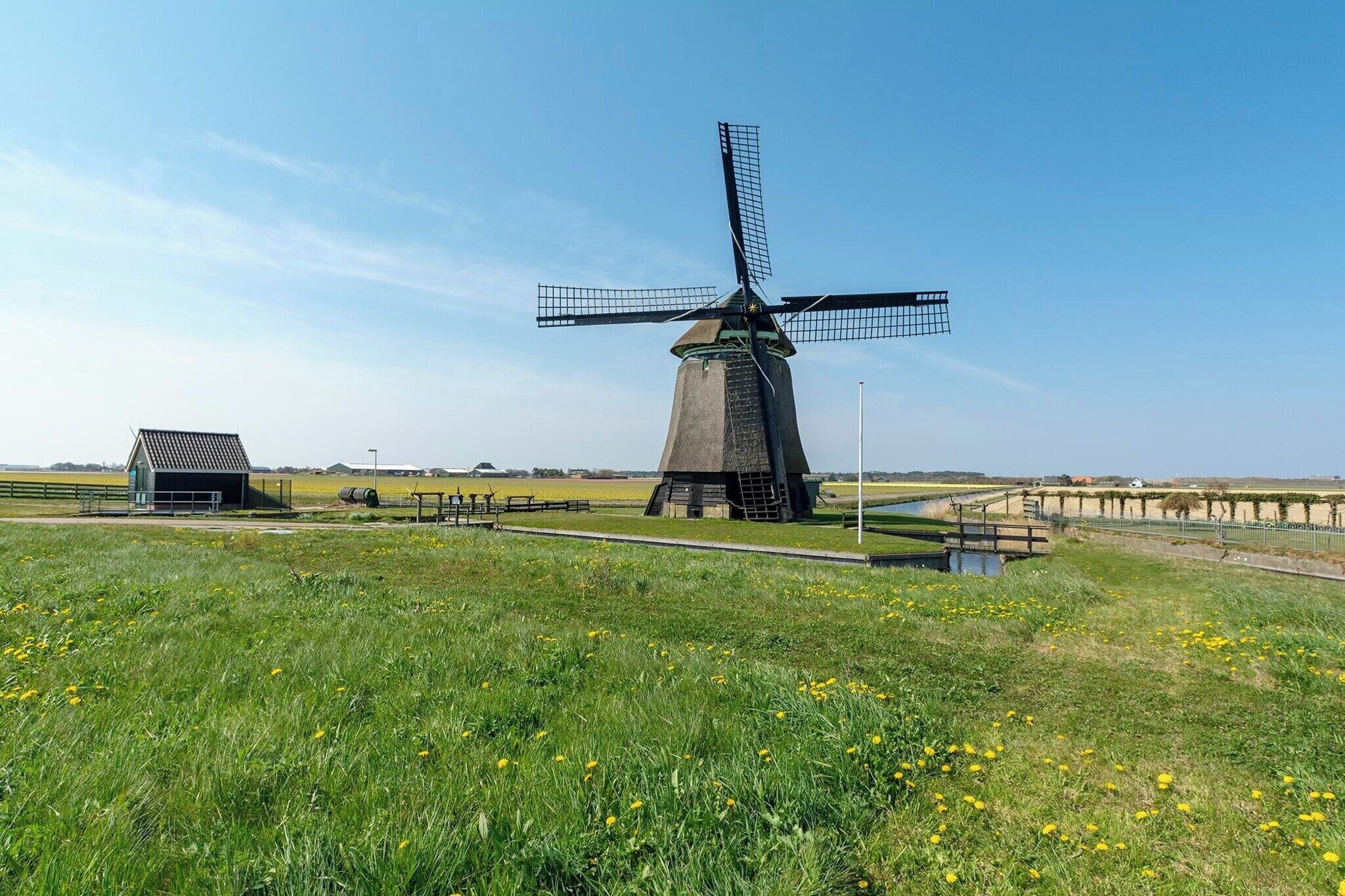 A windmill in a grassy field with a small building nearby.