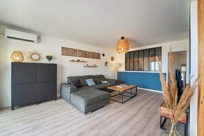 A modern living room with a sectional sofa, a coffee table, decorative wall art, and a hanging light fixture. - Sur le Port de Hyères-5 min de la Plage-calme (Hyères)