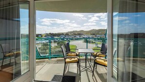 A balcony with a view of a parking lot and hills.