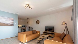 A modern living room with a sofa set, a TV, and a dining area.