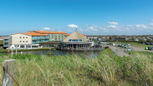 A waterfront hotel with a central building featuring a round, glass-roofed structure.