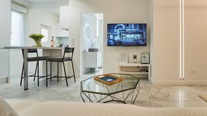 A modern kitchen with a dining area, a TV mounted on the wall, and a glass coffee table. - La Perle du Mourillon-wifi-spacieux (Toulon)