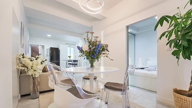 A modern dining area with a round table, clear chairs, and a vase of flowers. - La Perle du Mourillon-wifi-spacieux (Toulon)