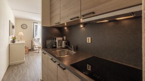 A modern kitchen with wooden cabinets, a black countertop, a built-in sink, and a stove. - Apartment 189 in Julianadorp aan Zee (Julianadorp aan Zee)