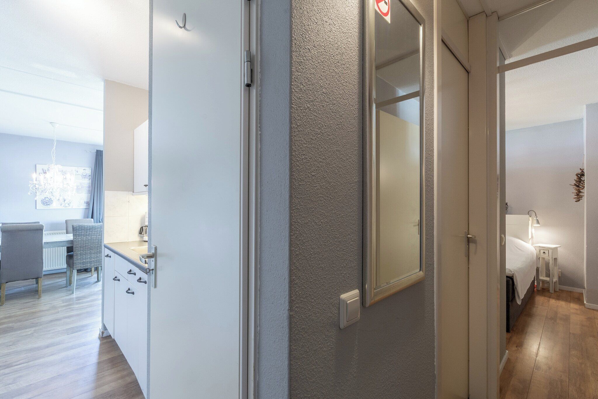 A modern hotel room with a kitchenette, a dining area, and a bathroom.