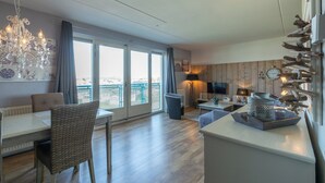 A modern living room with a dining area, large windows, and a cozy fireplace. - Strandslag 193 charming apartment for 4-person (Julianadorp aan Zee)