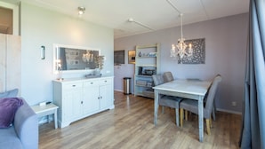 A modern kitchen with white cabinetry, a dining table, and a chandelier. - Strandslag 193 charming apartment for 4-person (Julianadorp aan Zee)