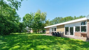 Un edificio moderno con fachada de ladrillo, ventanas amplias y un patio con mobiliario exterior.