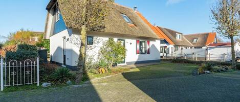 Ein Haus mit schrägem Dach, einem kleinen Fenster und einer weißen Fassade.
