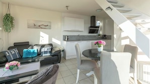 A modern living space with a sofa, dining table, and kitchen area.