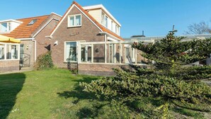A two-story house with a brick facade, a conservatory, and a well-maintained lawn.