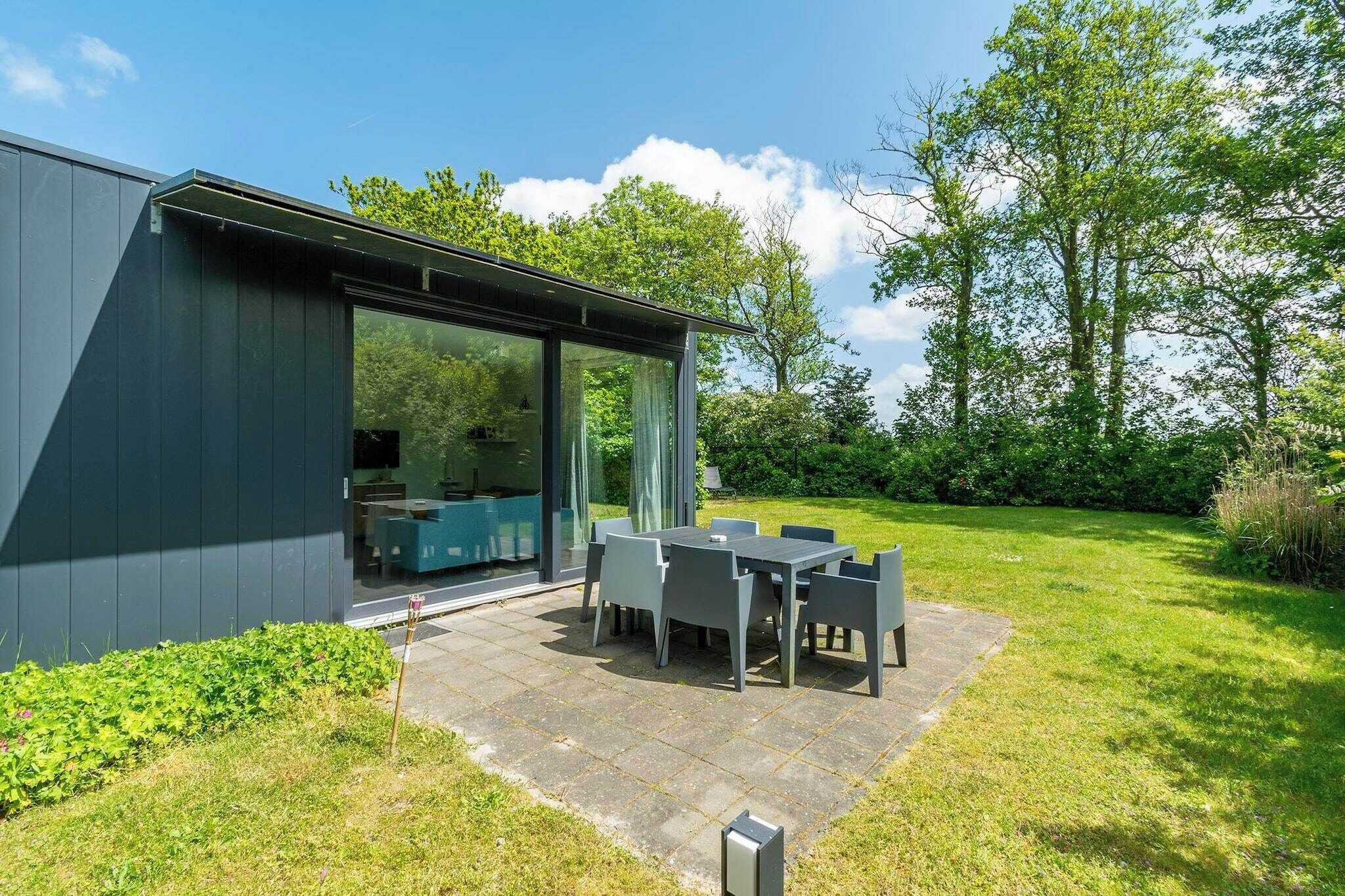 Ein modernes Haus mit einer Terrasse, komplett mit Tisch und Stühlen.