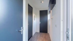 A narrow hallway with dark and light walls, a ceiling light, and a door at the end. - Bungalow near Dutch Beach and Bulb Fields (Sint Maartensvlotbrug)