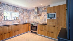 Una cocina con baldosas estampadas, armarios de madera, estufa y microondas.