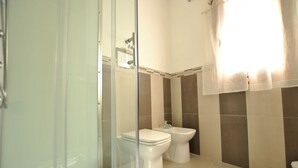 Et moderne badeværelse med en glas brusekabine, toilet og bidet.