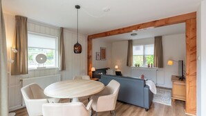 A cozy room with a round table, chairs, a sofa, and a desk with a lamp. - Holiday home Effe Sprage in Callanstoog Centre (Callantsoog)