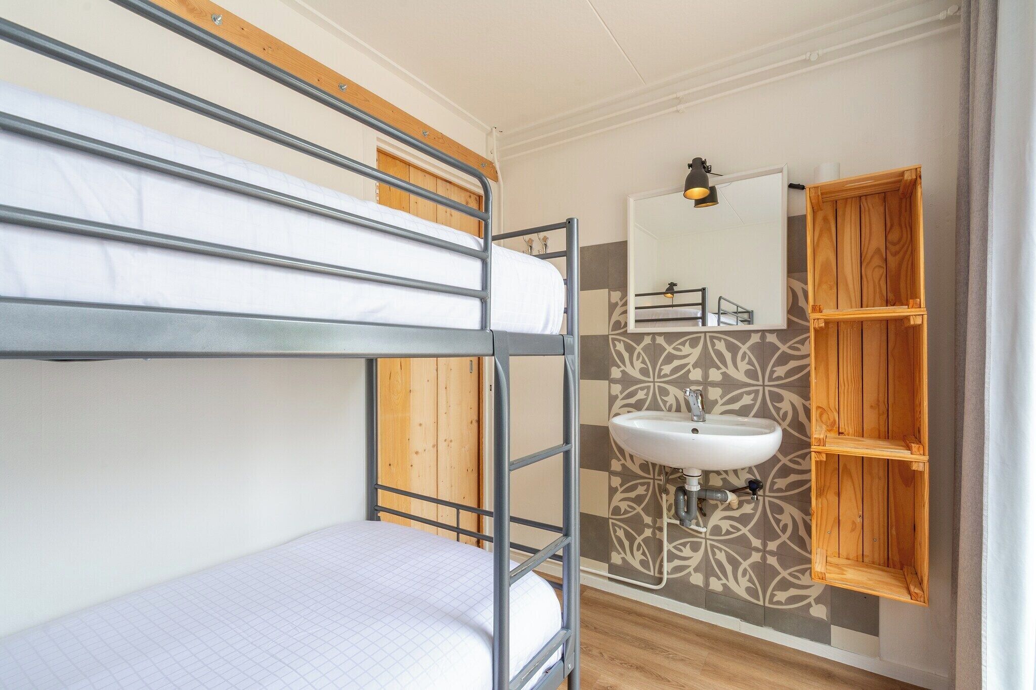 A bunk bed room with a wooden ceiling, a wall-mounted sink, and a mirror.