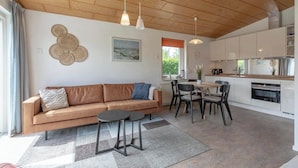Ett modernt vardagsrum med en soffa, ett soffbord och en matplats.