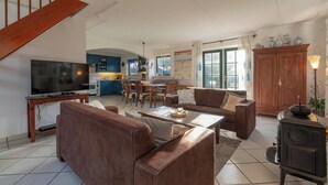 A spacious living room with a television, sofas, a coffee table, and a wooden cabinet. - De Buitenplaats 145 villa with sauna (Callantsoog)