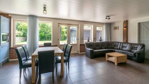 Un amplio salón con una mesa de comedor de madera, un sofá de cuero negro y una mesa auxiliar.