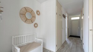 A hallway with a white bench, a door, and wall decor.