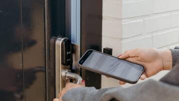 Une personne utilisant un téléphone intelligent pour interagir avec un système de verrouillage de porte.