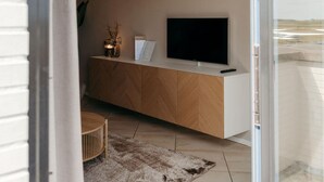 A modern living room with a flat-screen TV on a wooden cabinet, a small table, and a rug.