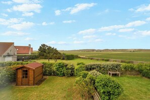 Een landelijk gelegen bezit met een houten schuur, een woning en een omheind veld.