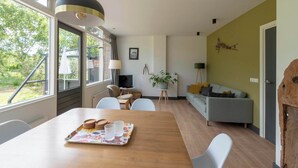 A modern living room with a dining table, sofa, and a large window. - De Zeester 4-person holiday home n De Koog (Callantsoog)
