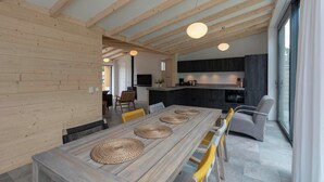 Eine moderne Küche mit dunklen Schränken, einem Holztisch mit gewebten Tischsets und einem großen Fenster, das natürliches Licht hereinlässt.