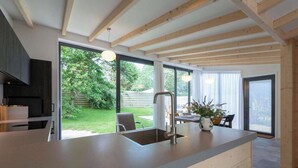 Eine moderne Küche mit einer großen Kochinsel, einer eingebauten Spüle und einem Essbereich mit Tisch und Stühlen.